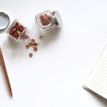 pines color cobre, cuaderno y un bolígrafo sobre un escritorio blanco